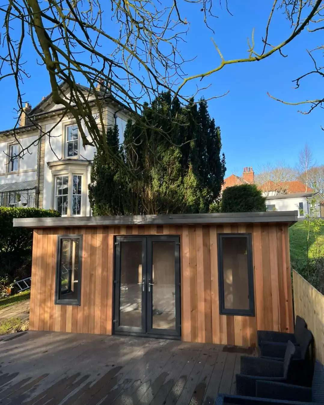 Cedar-clad garden room with black doors and windows