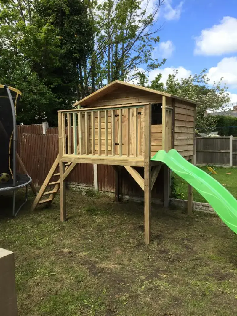 Raised timber playhouse with green slide